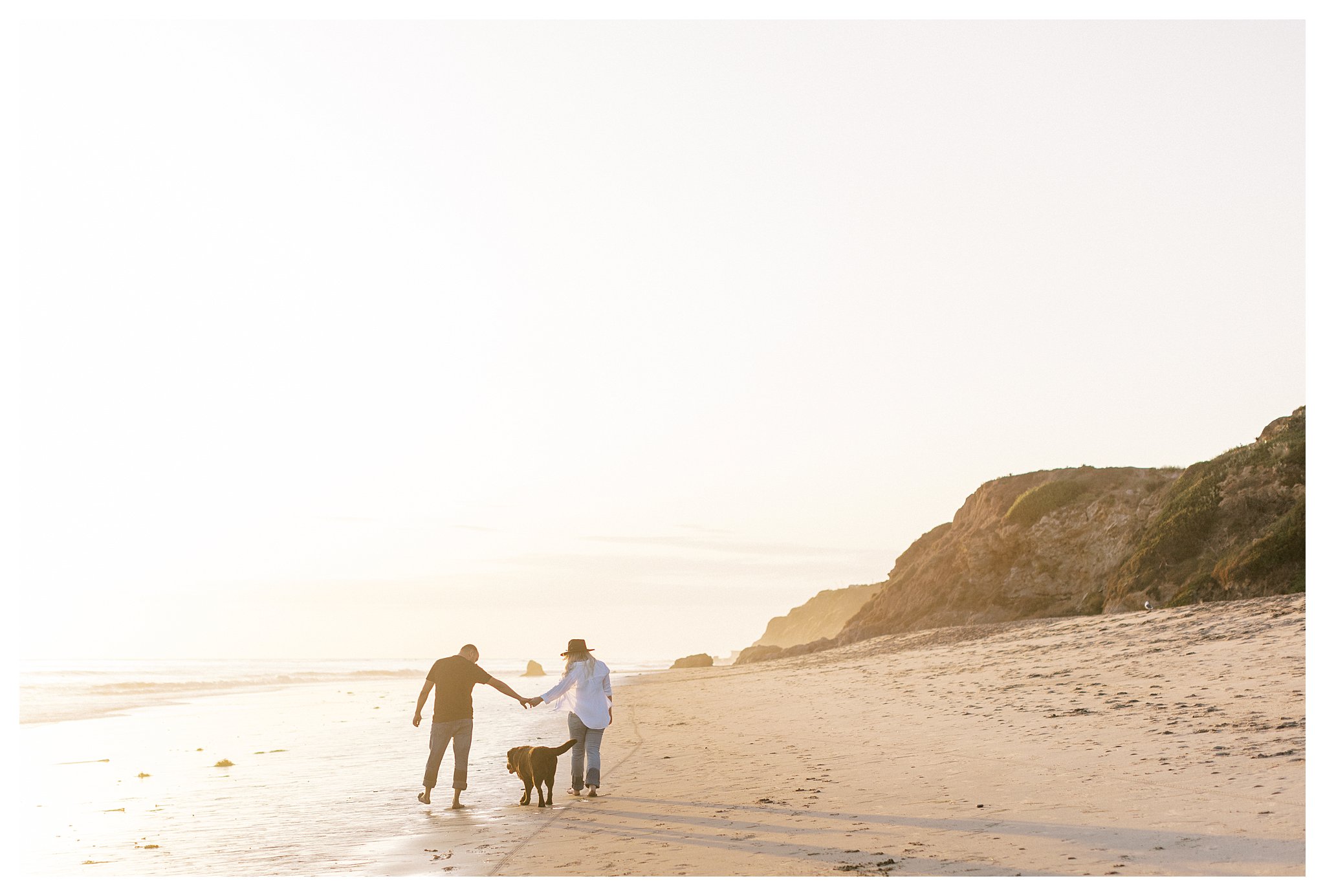 A couple walks their dog along the beach at sunset at Leo Carrillo. 