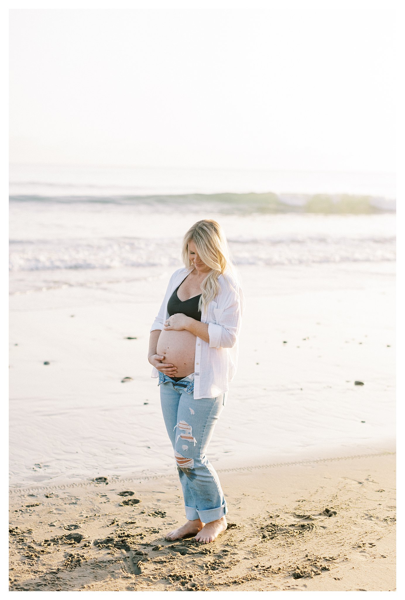 Mom-to-be looks at her pregnant belly in Malibu, Ca.