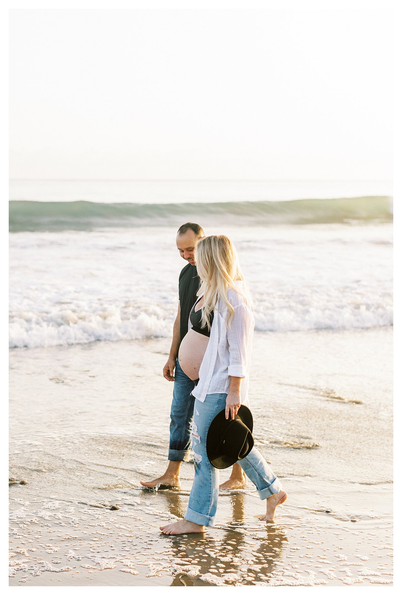 A pregnant couple walking along the beach in Malibu, Ca.