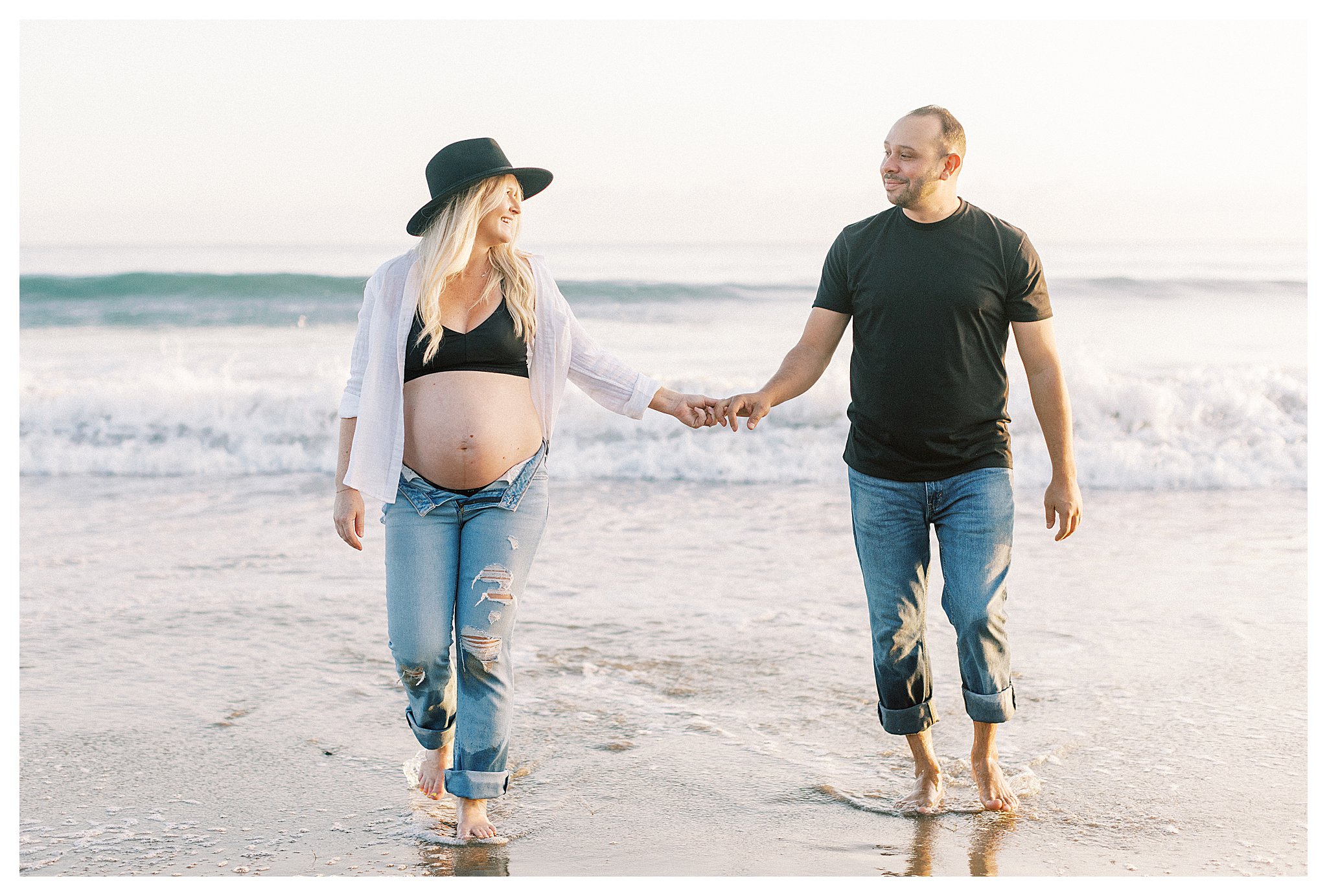 A pregnant couple walking in the water at Leo Carrillo Beach. 