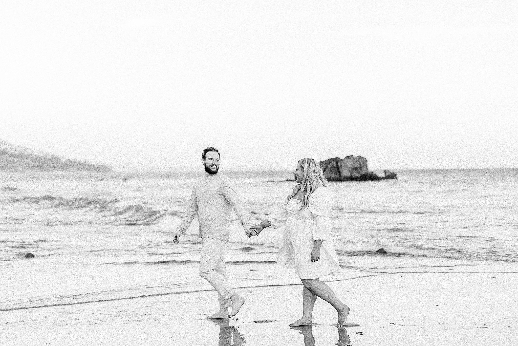 Engaged couple walking along the beach in Malibu, Ca.