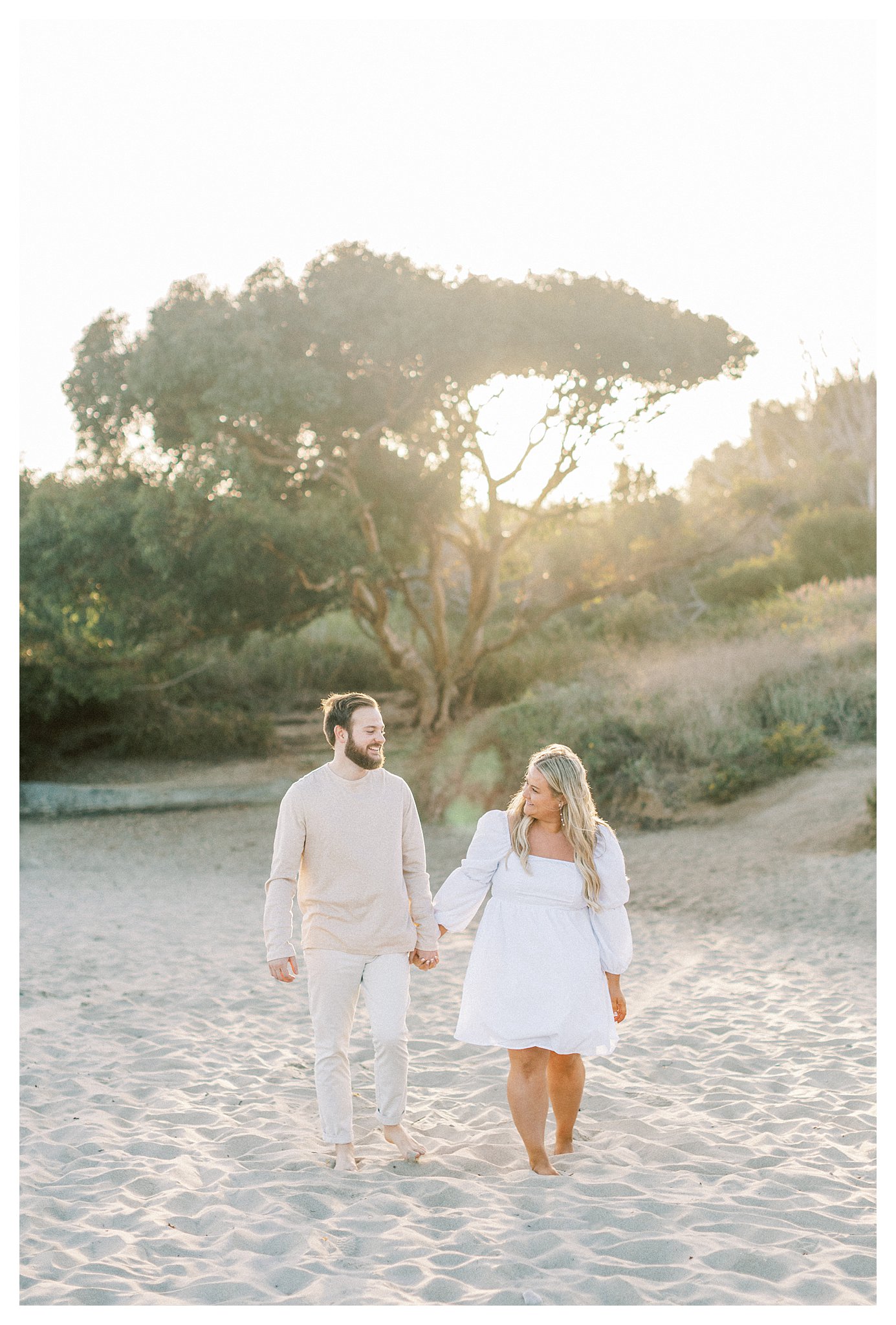 A couple walking on the beach while holding hands.