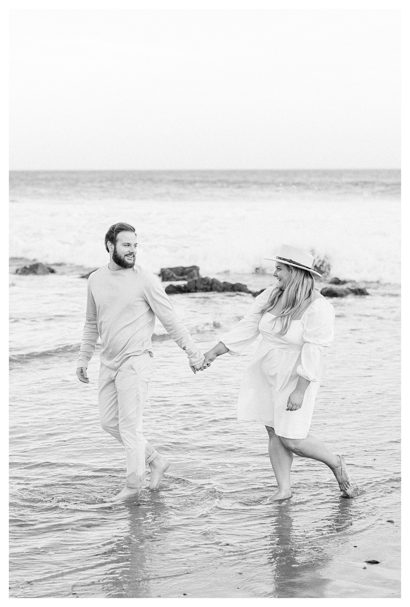 The engaged couple walking thru the water at Leo Carrillo beach in Malibu, Ca.