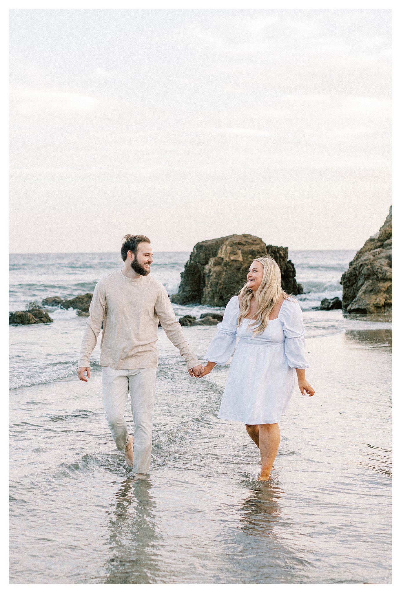 A couple walking together along the water during their engagement session in Malibu.