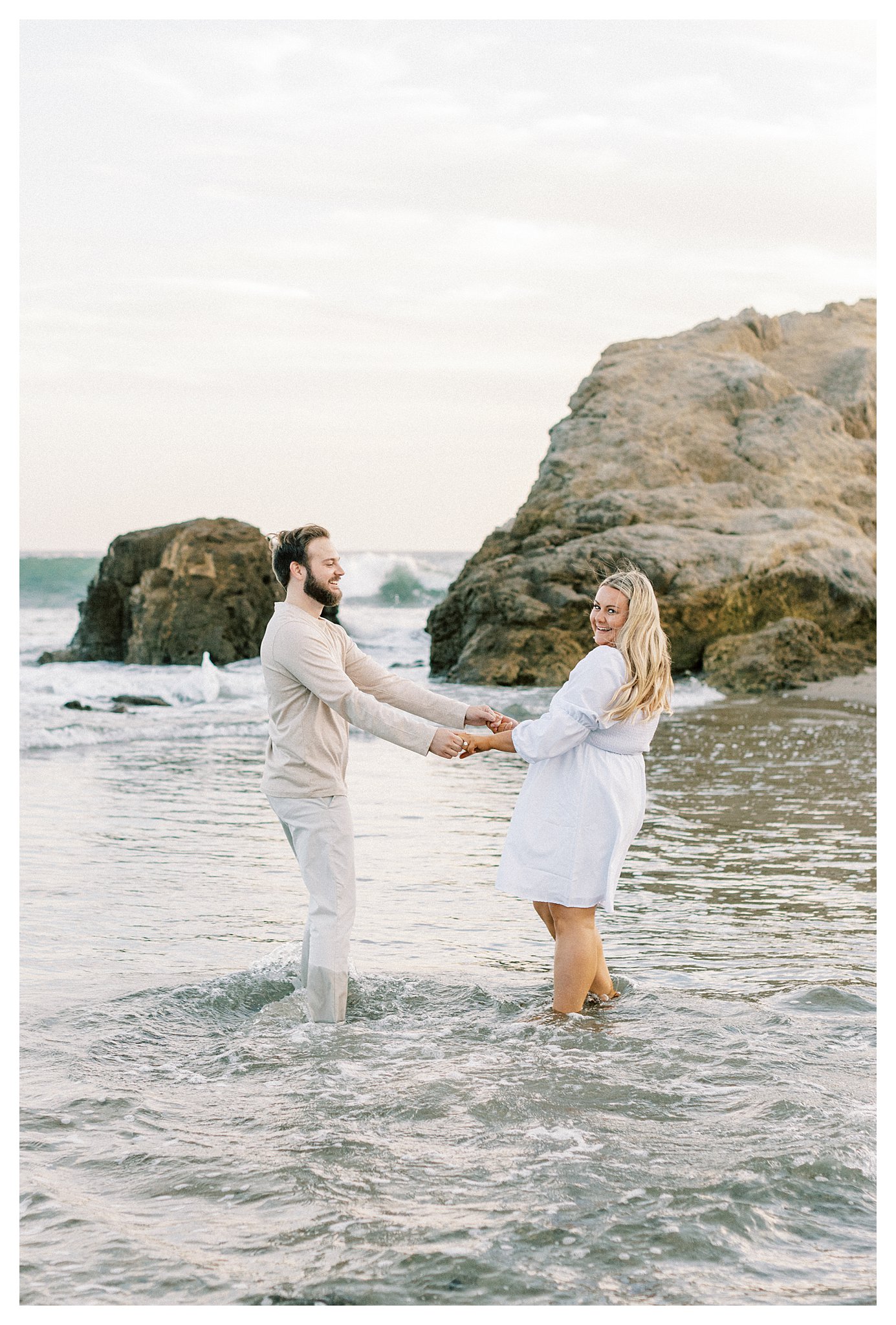 A couple holding hands while standing in water at Leo Carrillo Beach. 