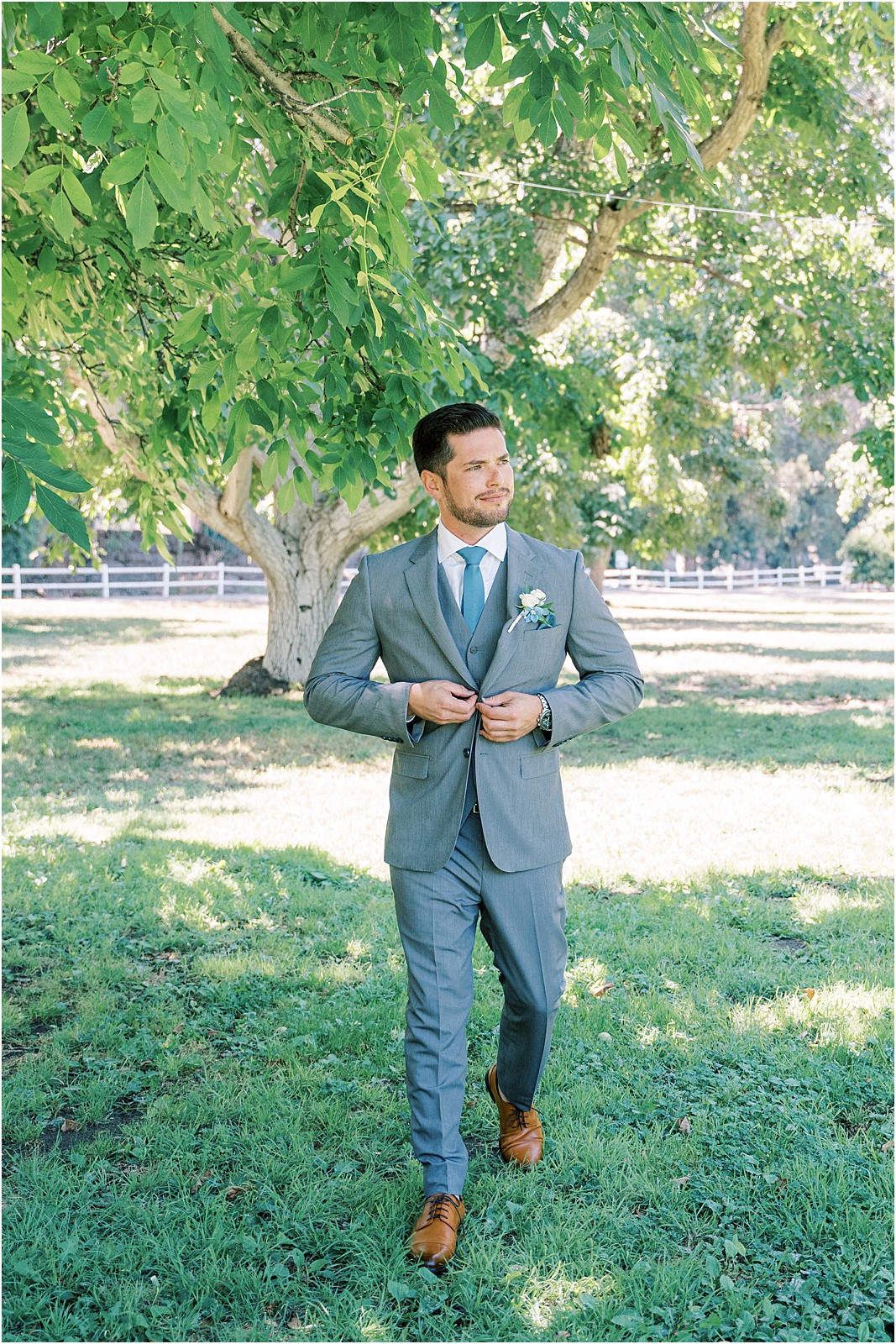 A groom buttoning his jacket in Moorpark, Ca.