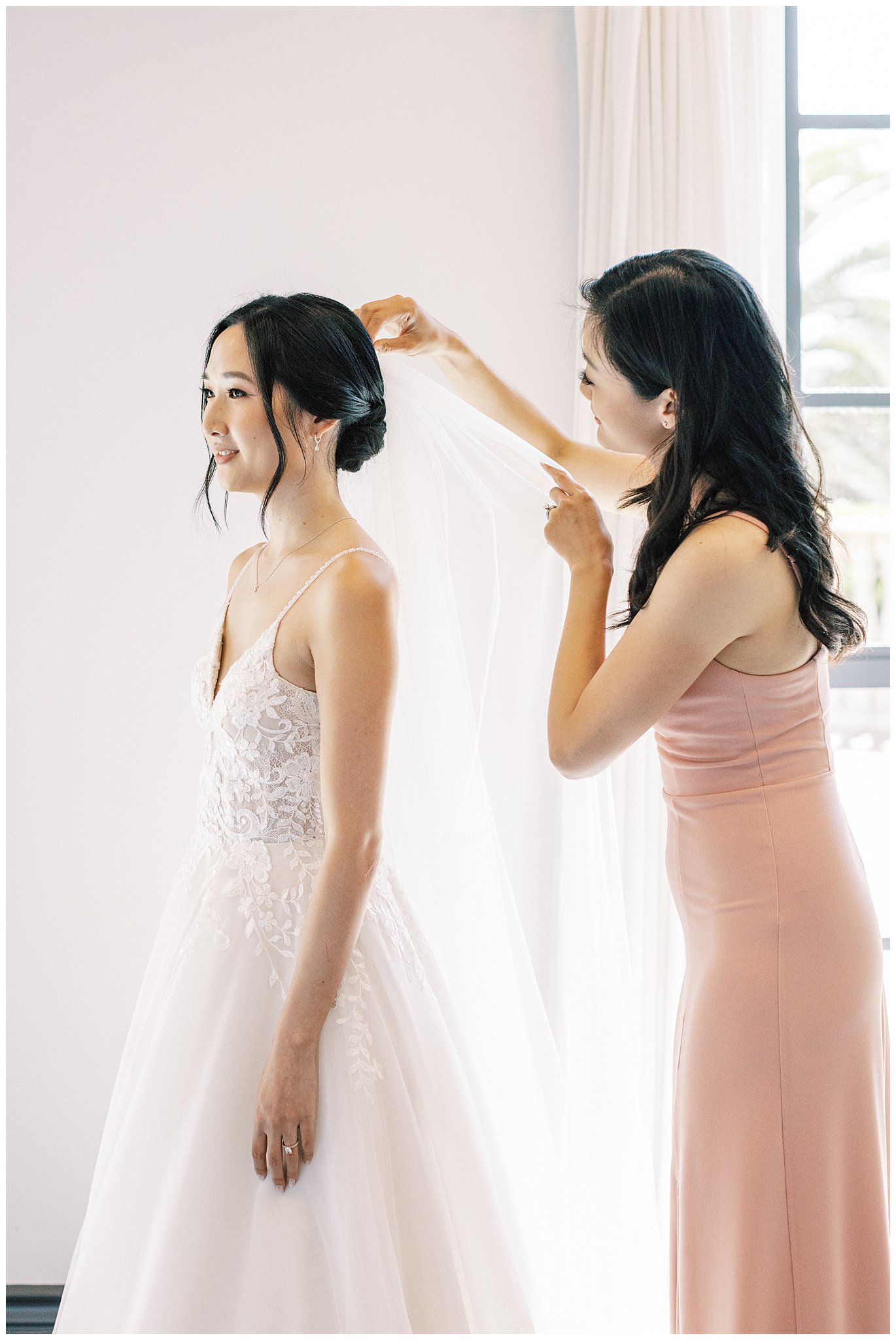 Maid of honor helping the bride with veil.