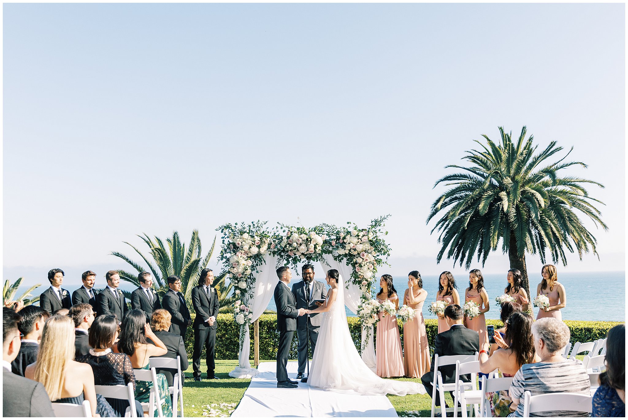 The bride and groom holding hands during the ceremony at Bel Air Bay Club in Pacific Palisades, Ca.