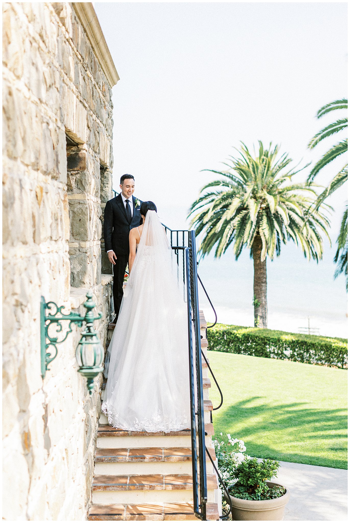 Groom smiling at bride on stairs.  