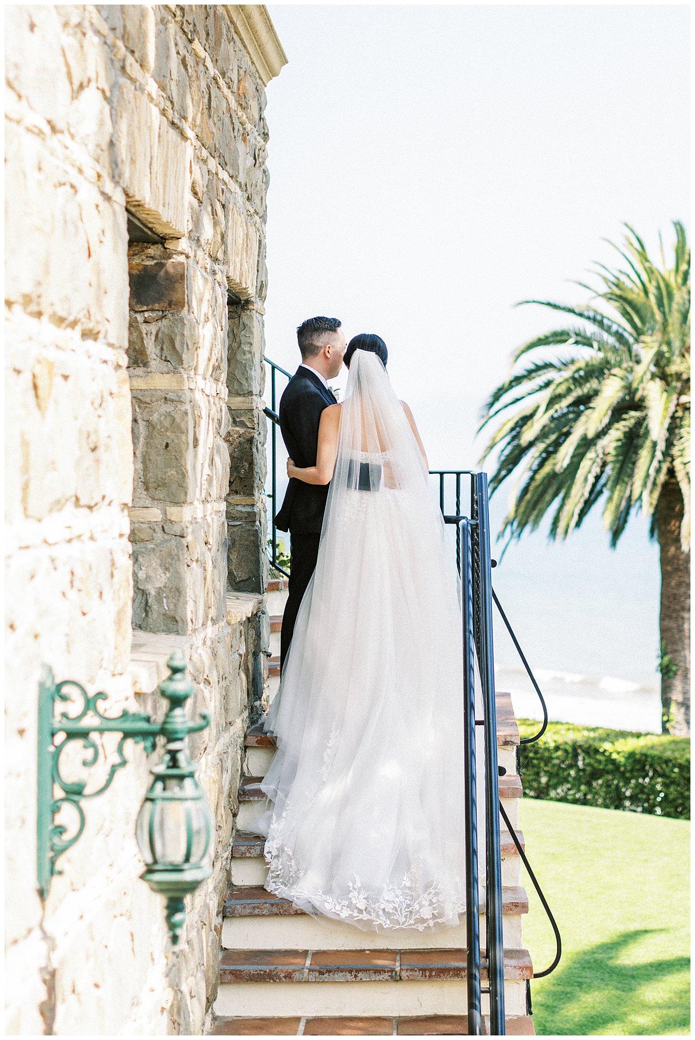 Bride and groom standing on the stairs looking at the ocean at Bel Air Bay Club.  