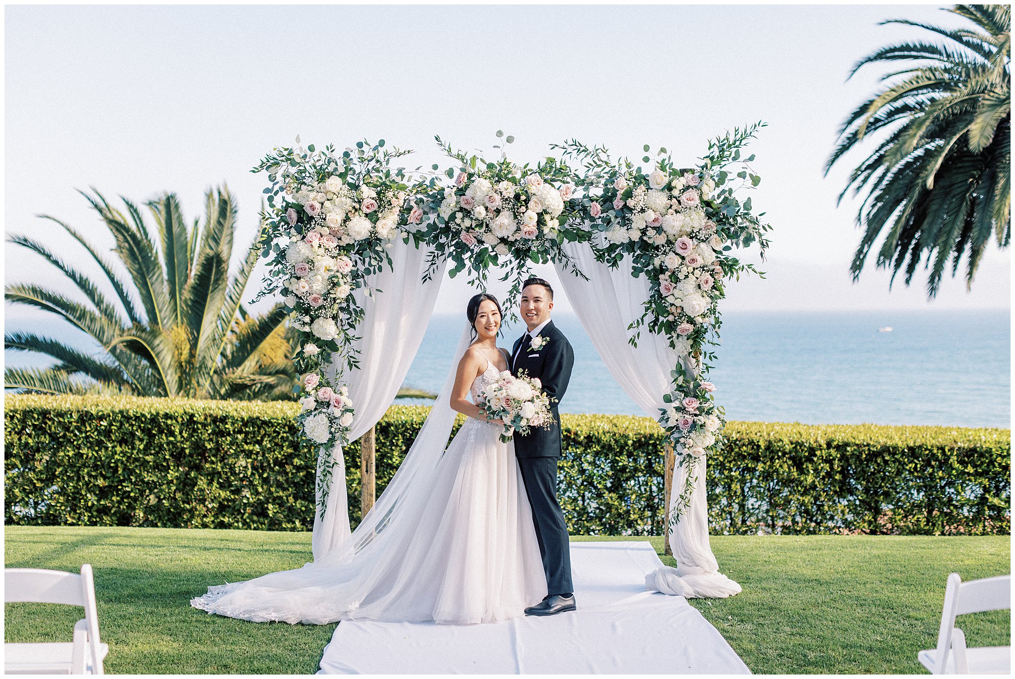 Newly married couple in front of wedding arch.  