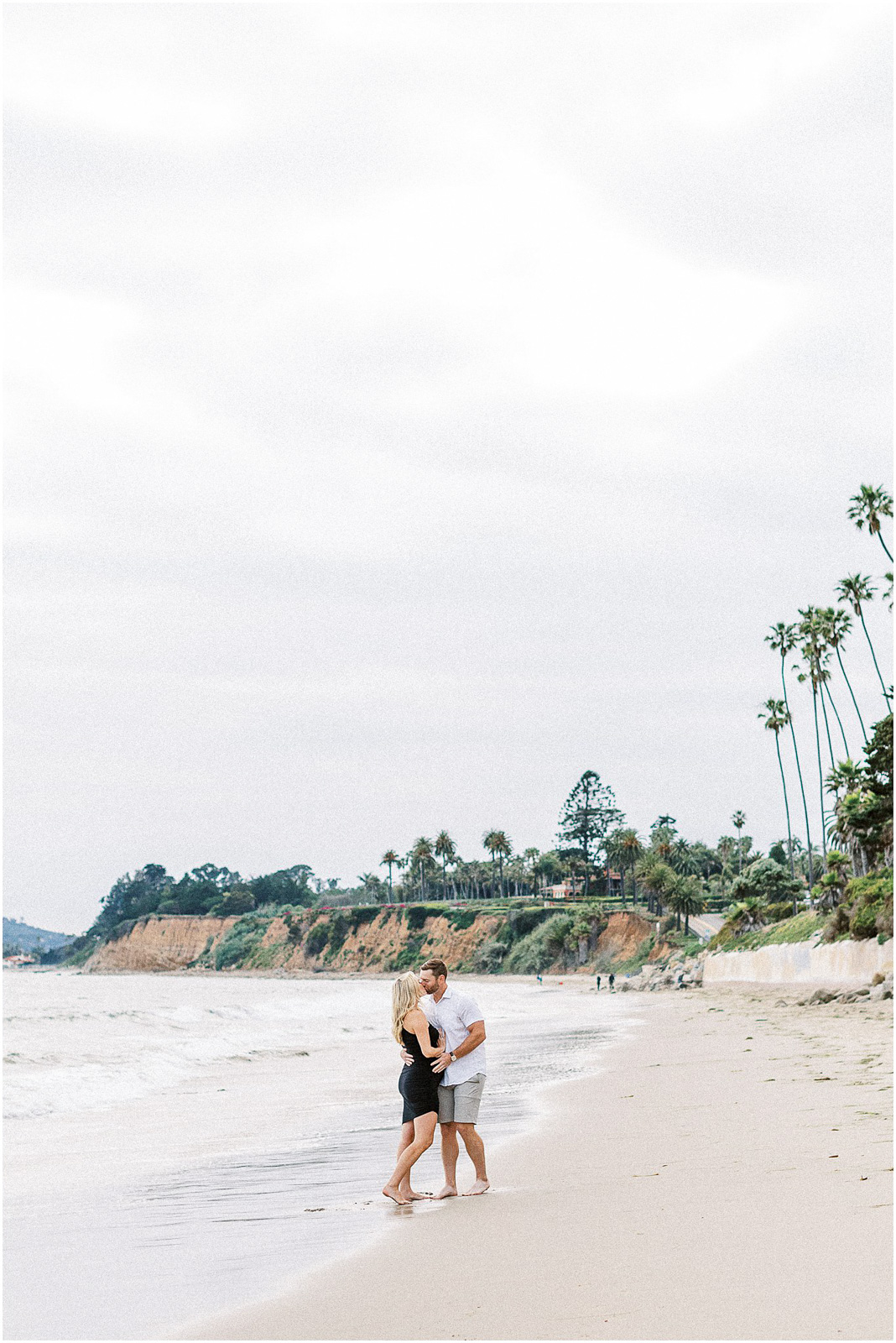 A man and woman kissing on the sand at Butterfly Beach in Montecito, Ca.