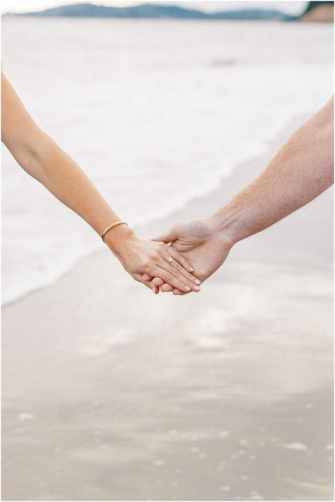 A husband and wife holding hands on the beach in so California.  