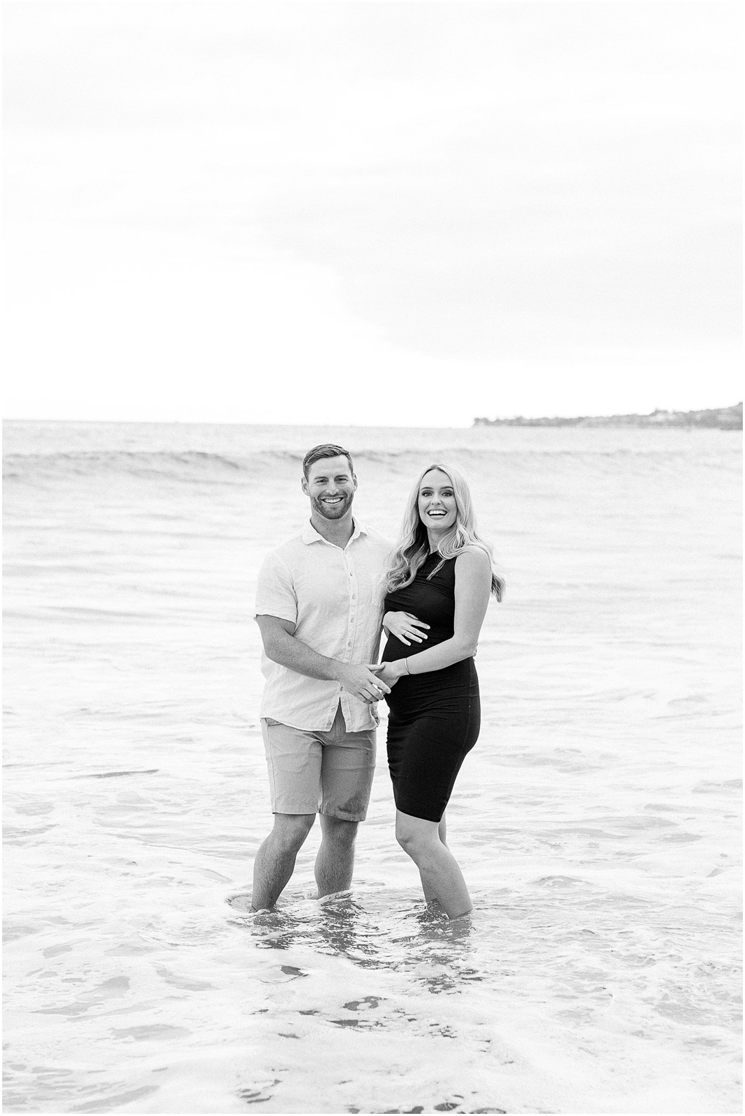 A pregnant couple laughing in the water at Butterfly Beach in Montecito, Ca.