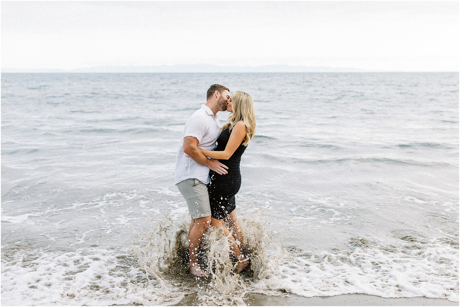 A pregnant couple kissing in the water at Butterfly Beach in Montecito, Ca.