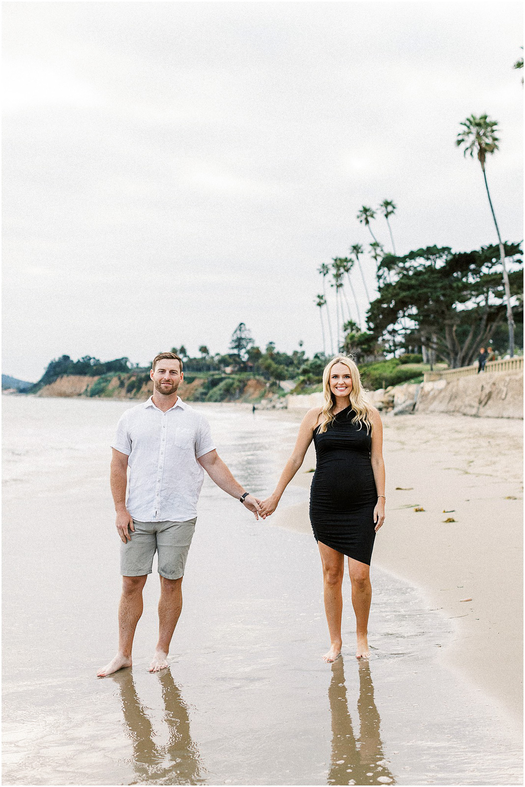 A man and woman holding hands on the beach in Montecito, Ca.