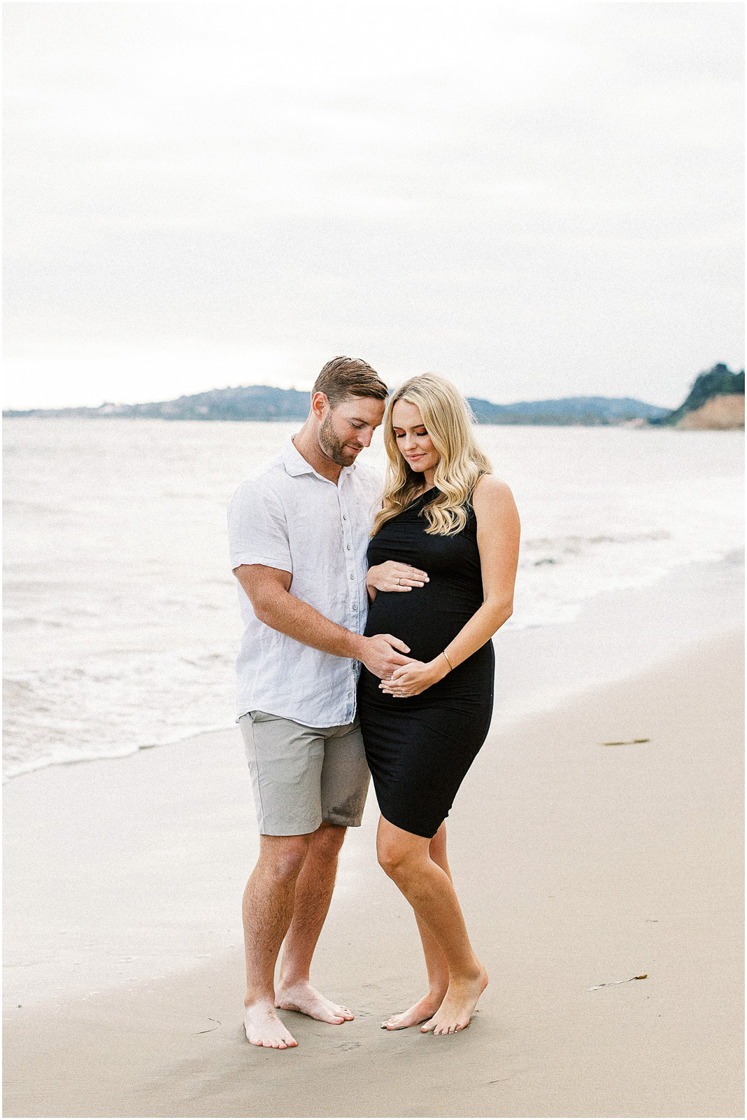 A pregnant couple on the sand at Butterfly Beach in Montecito, Ca.