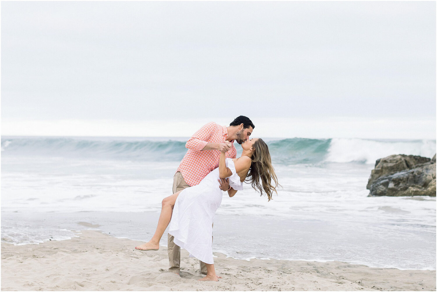 An engaged couple kissing in front of the ocean in Malibu, Ca.