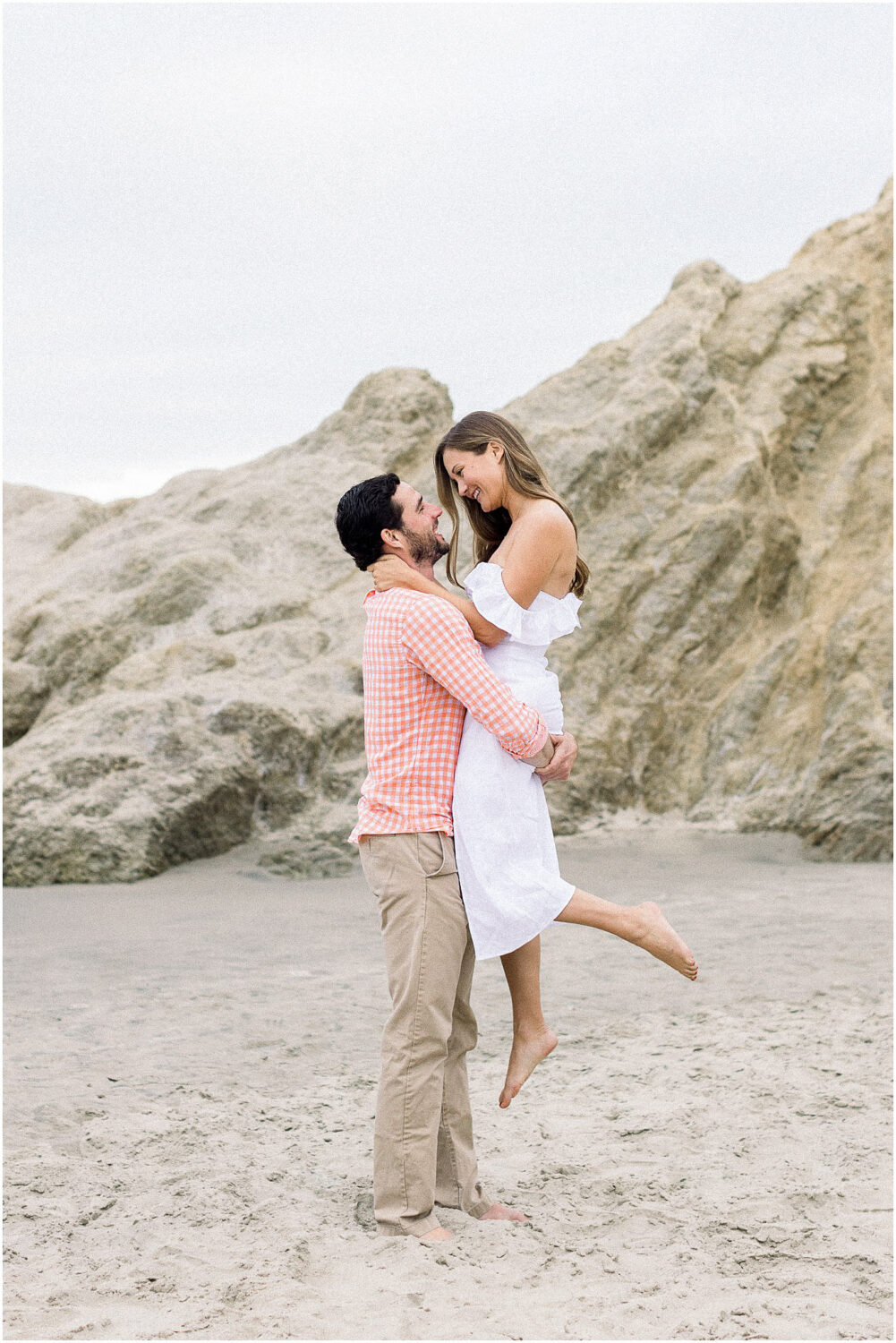 A couple smiling at each other on the beach in Malibu, Ca.