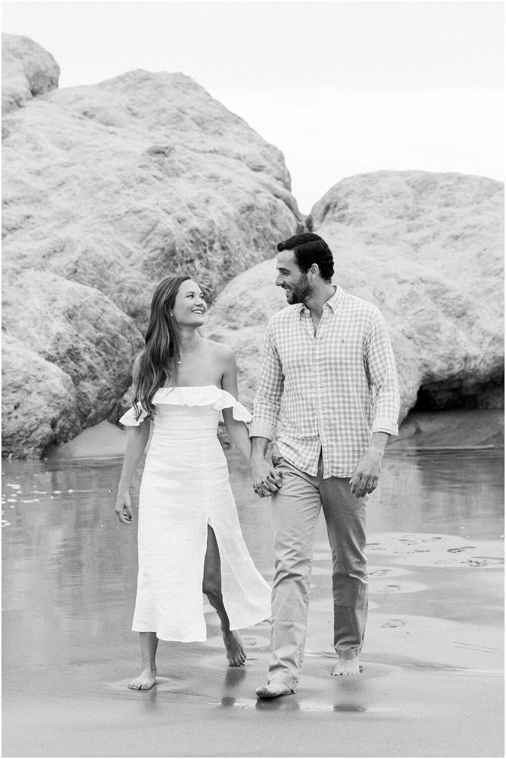 An engaged couple walking along the beach at Leo Carrillo Beach.