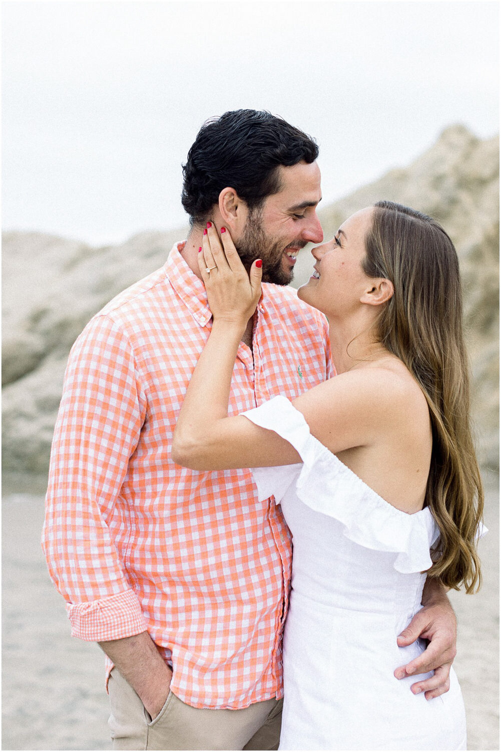 A couple gazing and smiling at each other on the beach in Malibu, Ca.