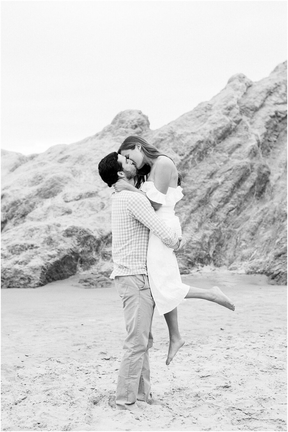 An engaged couple kissing on the sand in Malibu, Ca.