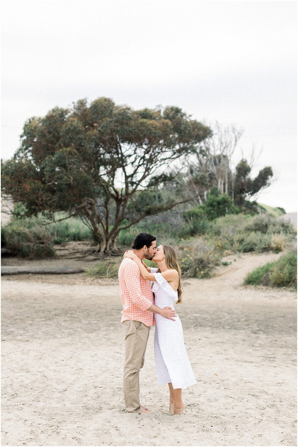 An engaged couple sharing a kiss at Leo Carrillo Beach.  