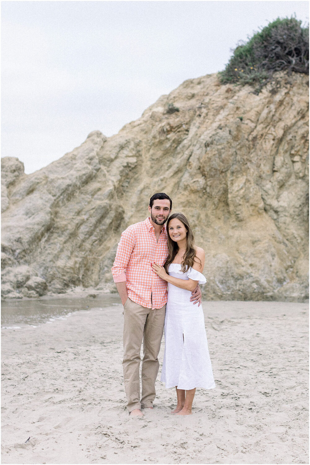 A couple smiling on the sand at Leo Carrillo beach in Malibu, Ca.