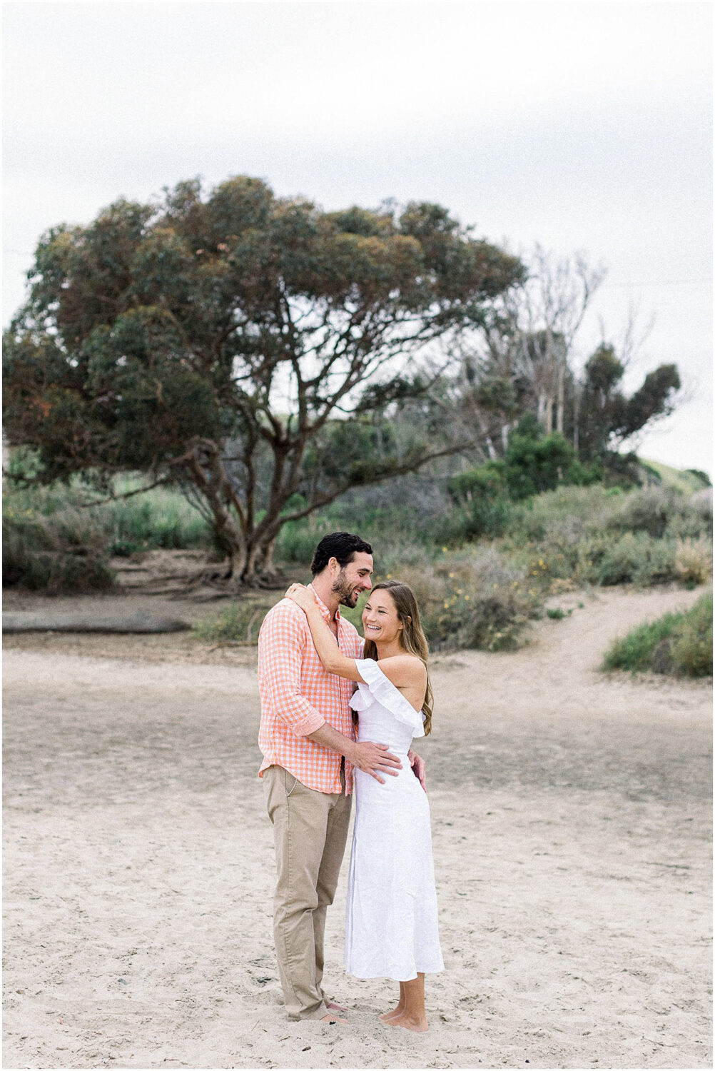 A man whispering into his girlfriends ear at Leo Carrillo beach.