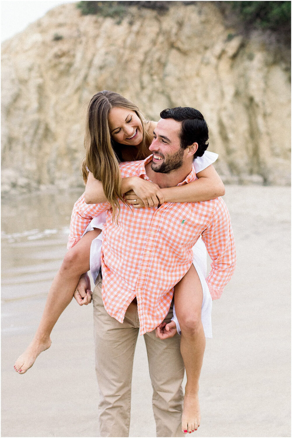 Engaged couple giving a piggyback on the beach at Leo Carrillo in Malibu, Ca.