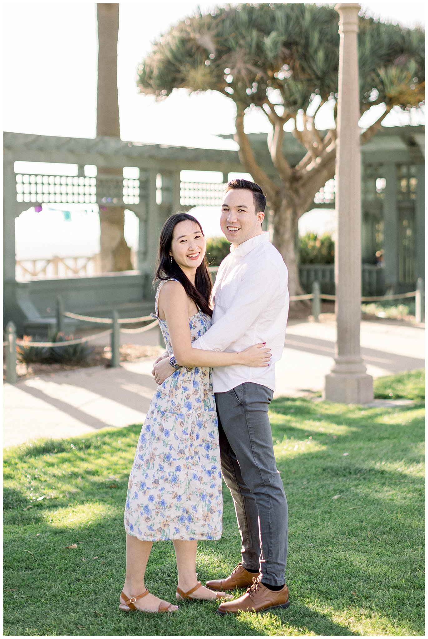 A couple smiling while taking a portrait during their engagement session.