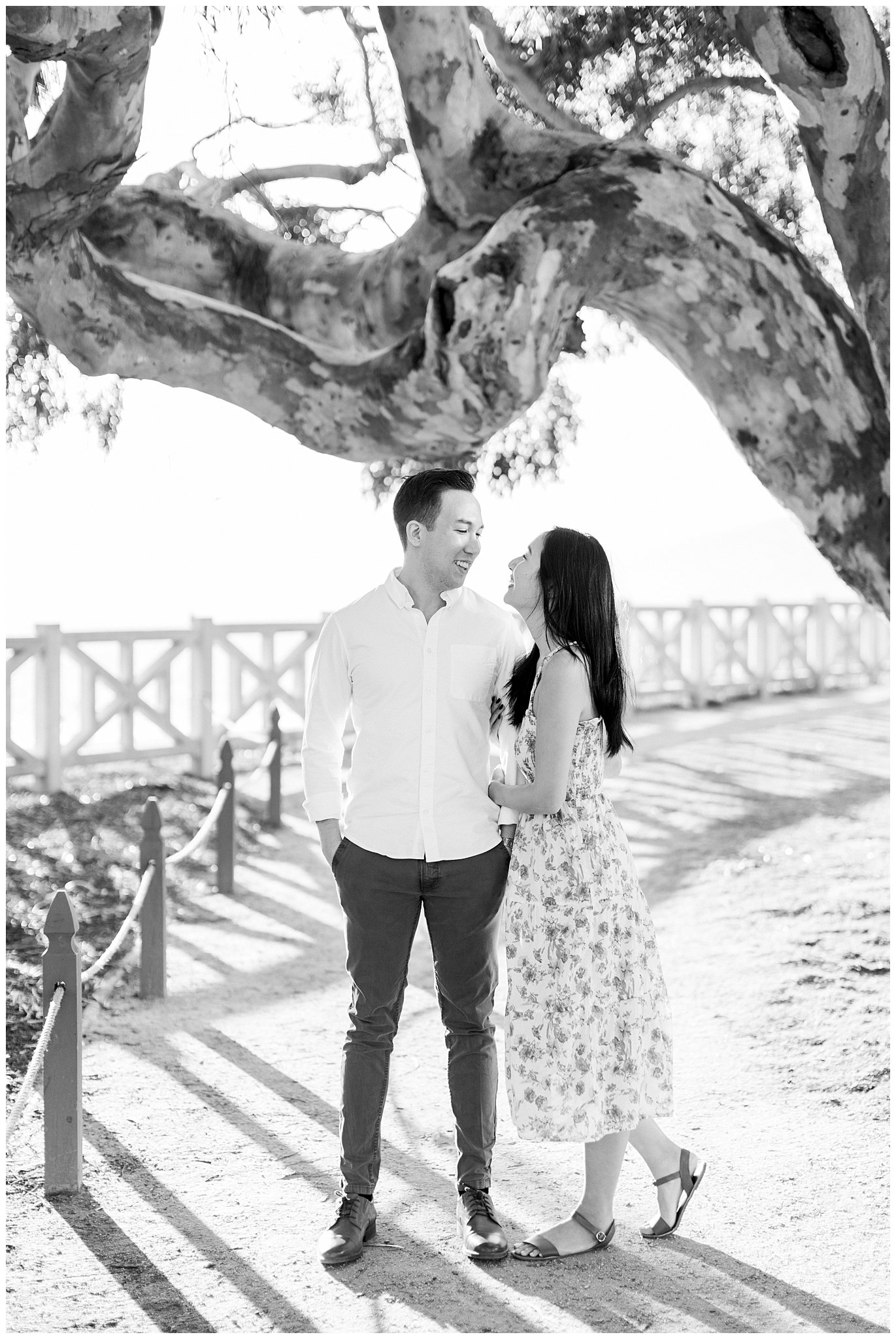 A couple laughing under a canopy of trees in Palisades Park during their engagement shoot.