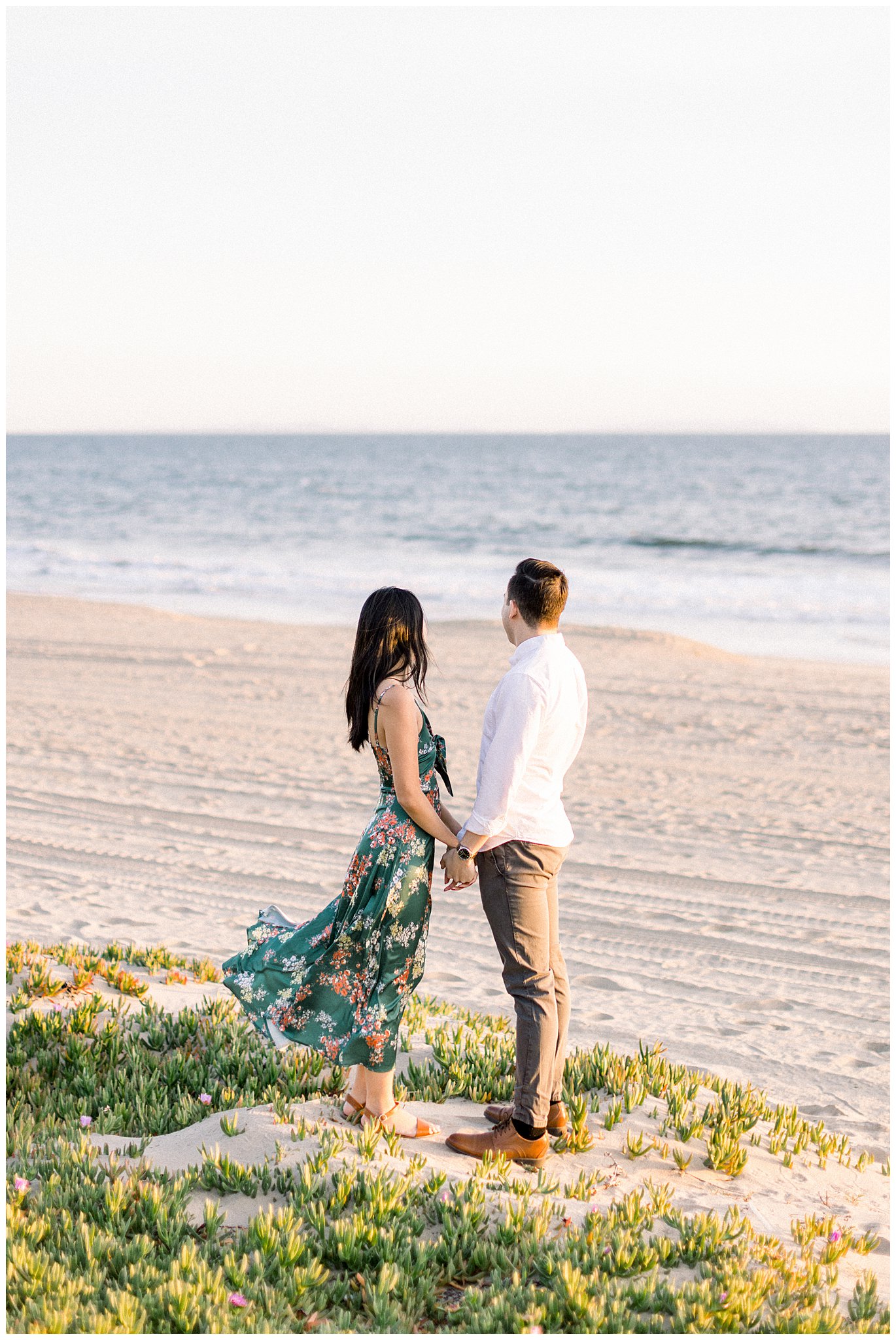 A couple holding hands and enjoying the ocean view during an engagement session at Will Rogers Beach.