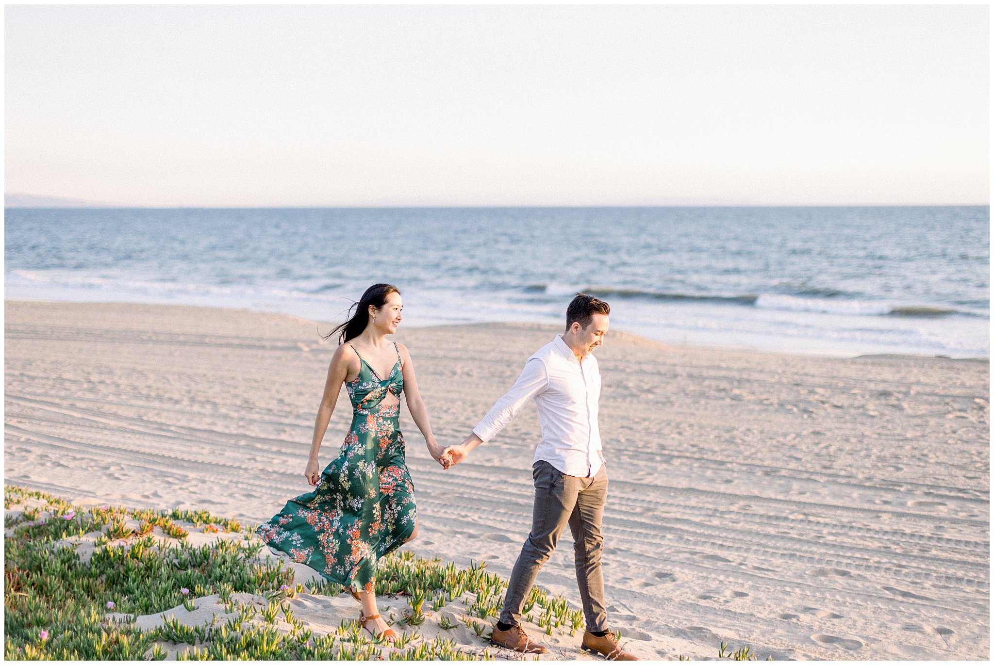 A couple walking hand-in-hand during an engagement session at Will Rogers Beach.