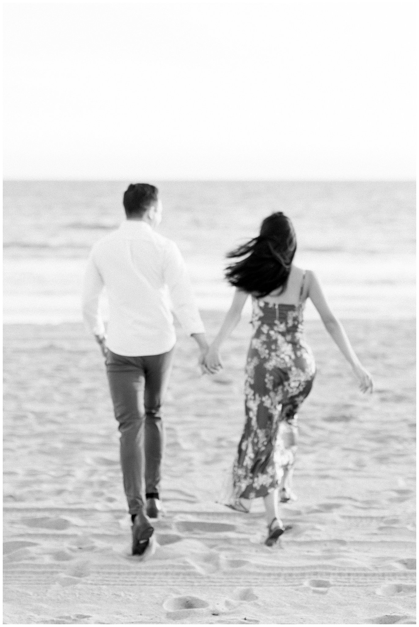 A couple jogging while holding hands on the sands of Will Rogers Beach.