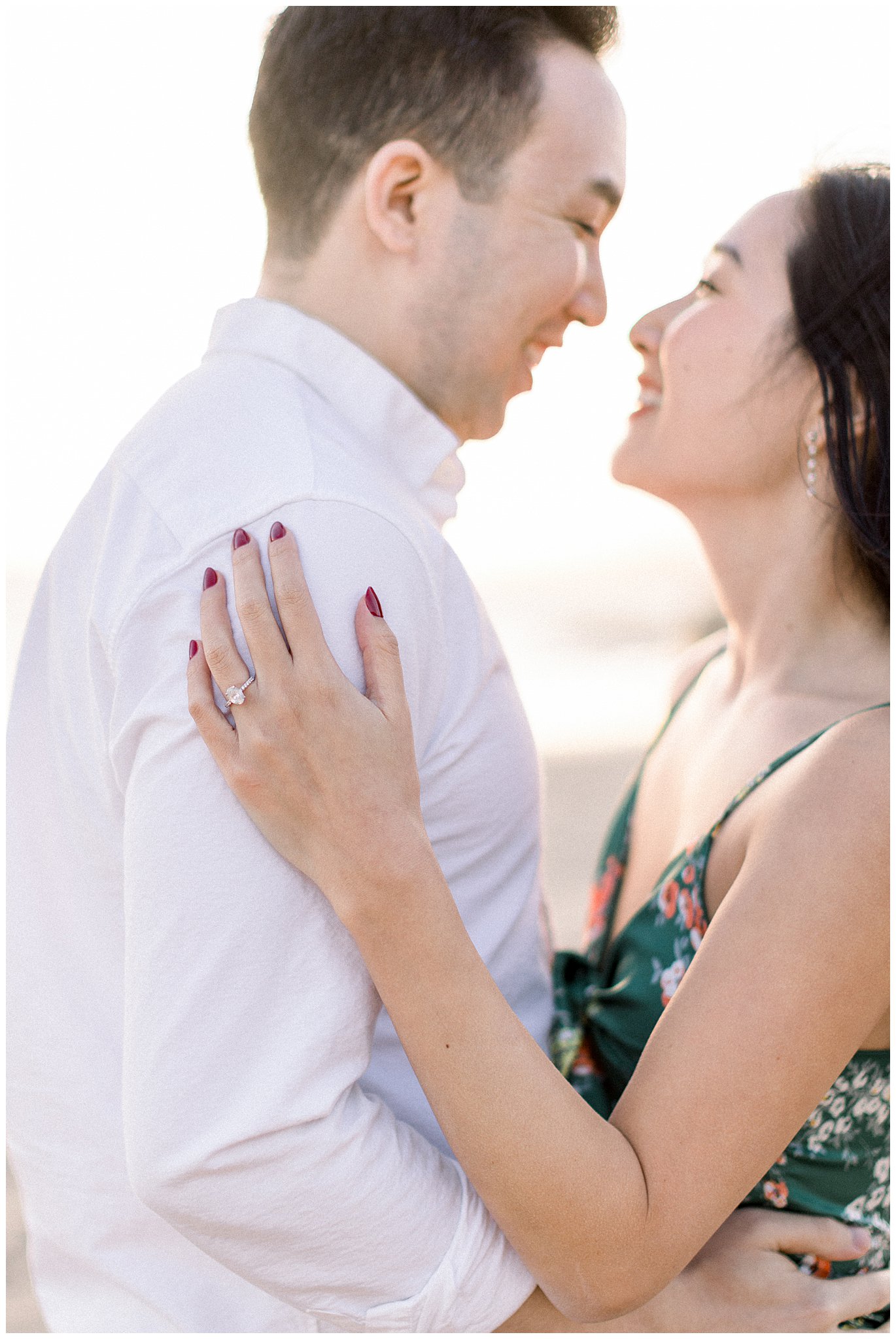 An engagement ring and a couple smiling during their engagement session at Will Rogers Beach.