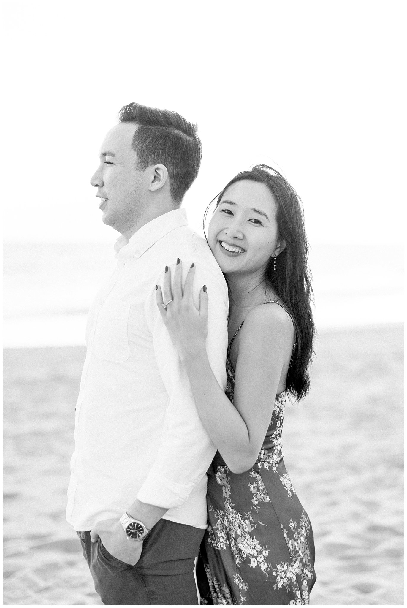 A woman hugging her fiance during their engagement session at Will Rogers Beach.  