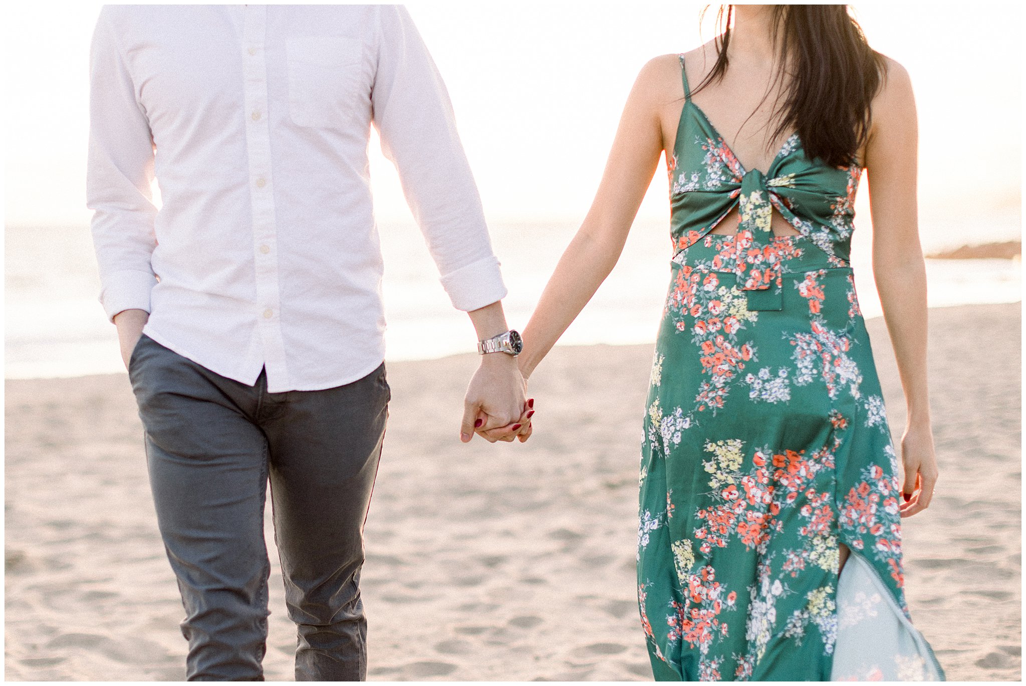 A couple holding hands during their engagement session at Will Rogers Beach.  