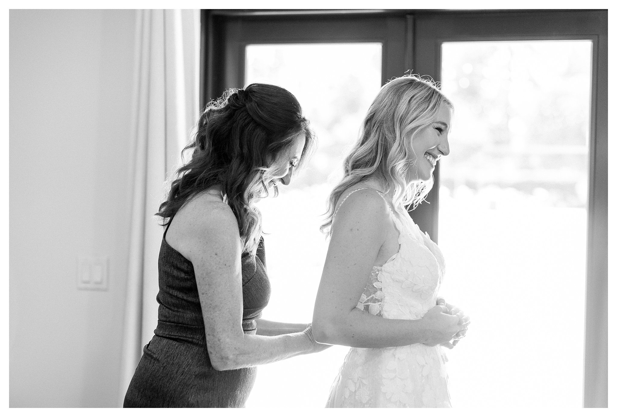 Mother of the bride assisting her daughter with the wedding dress.