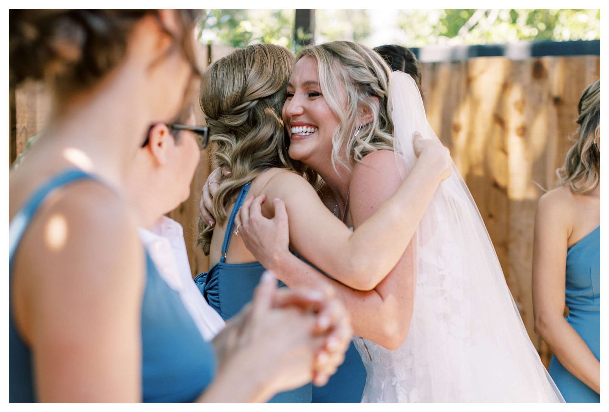 Bride and bridesmaid embrace on the wedding day.