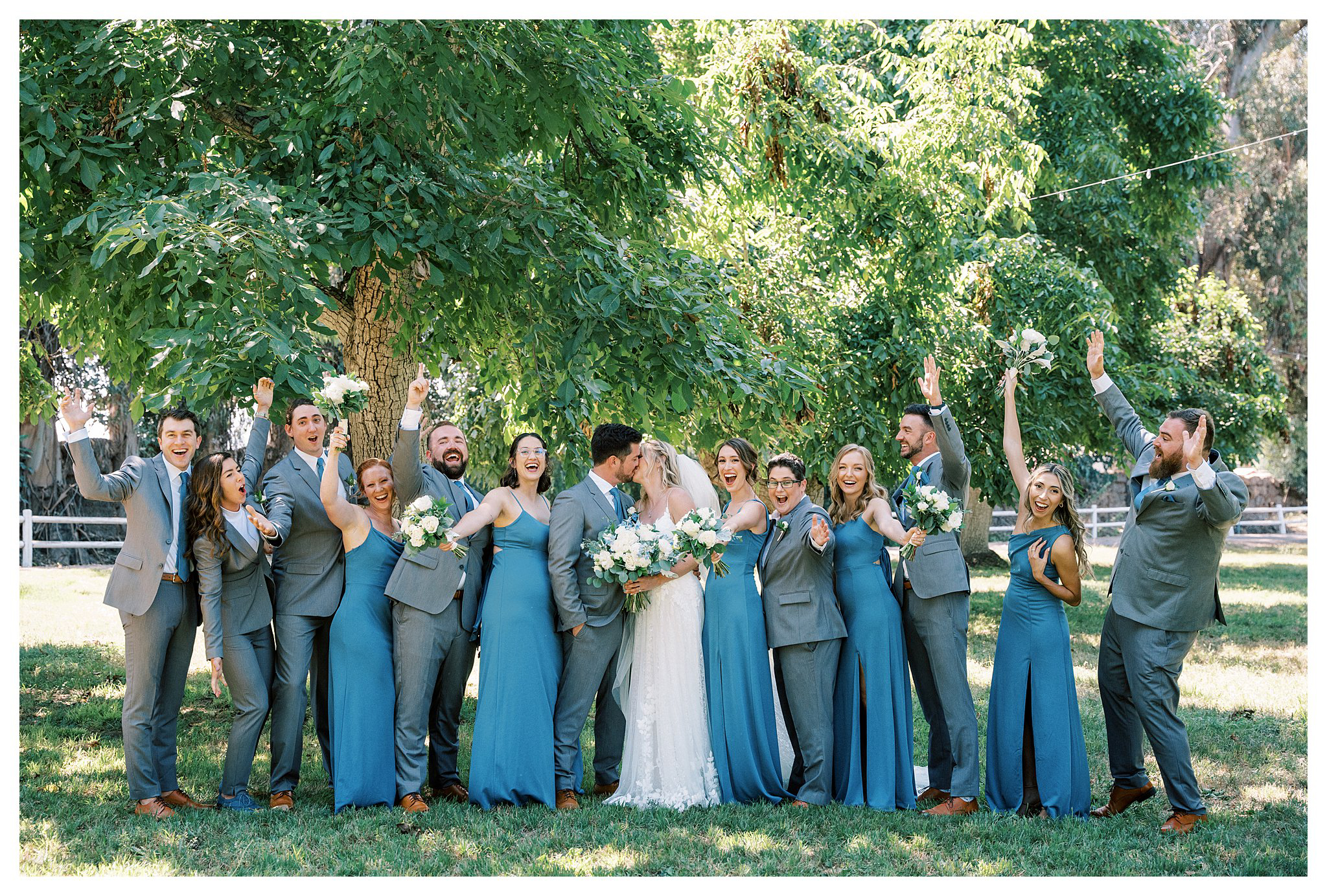 The wedding party getting excited while the bride and groom kiss.  