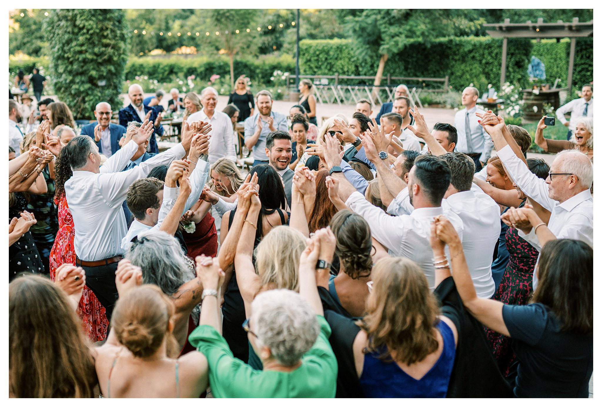 The newlyweds surrounded by family and friends at wedding.  