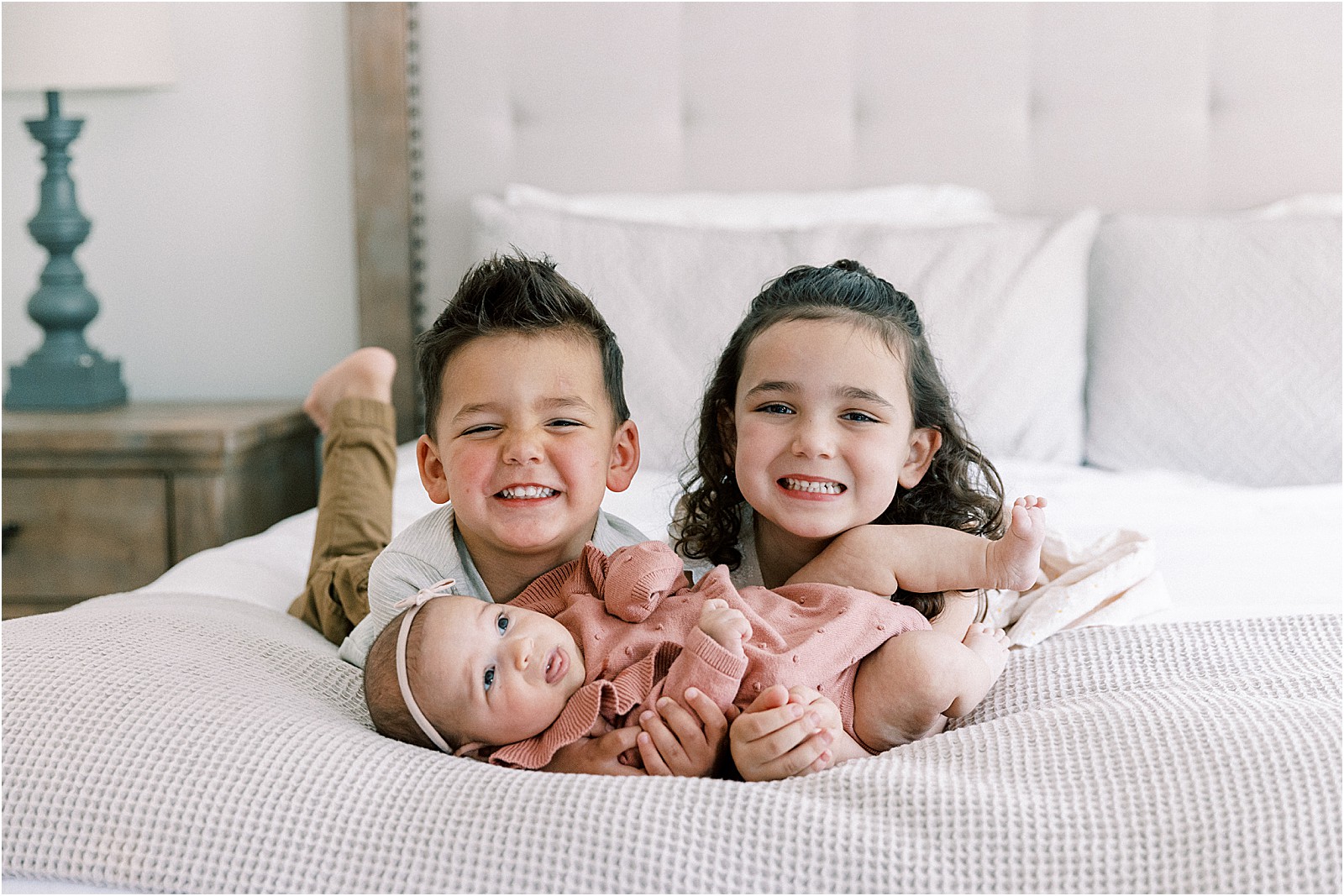 The three siblings posing for a portrait on the bed during a family photo session in Thousand Oaks.