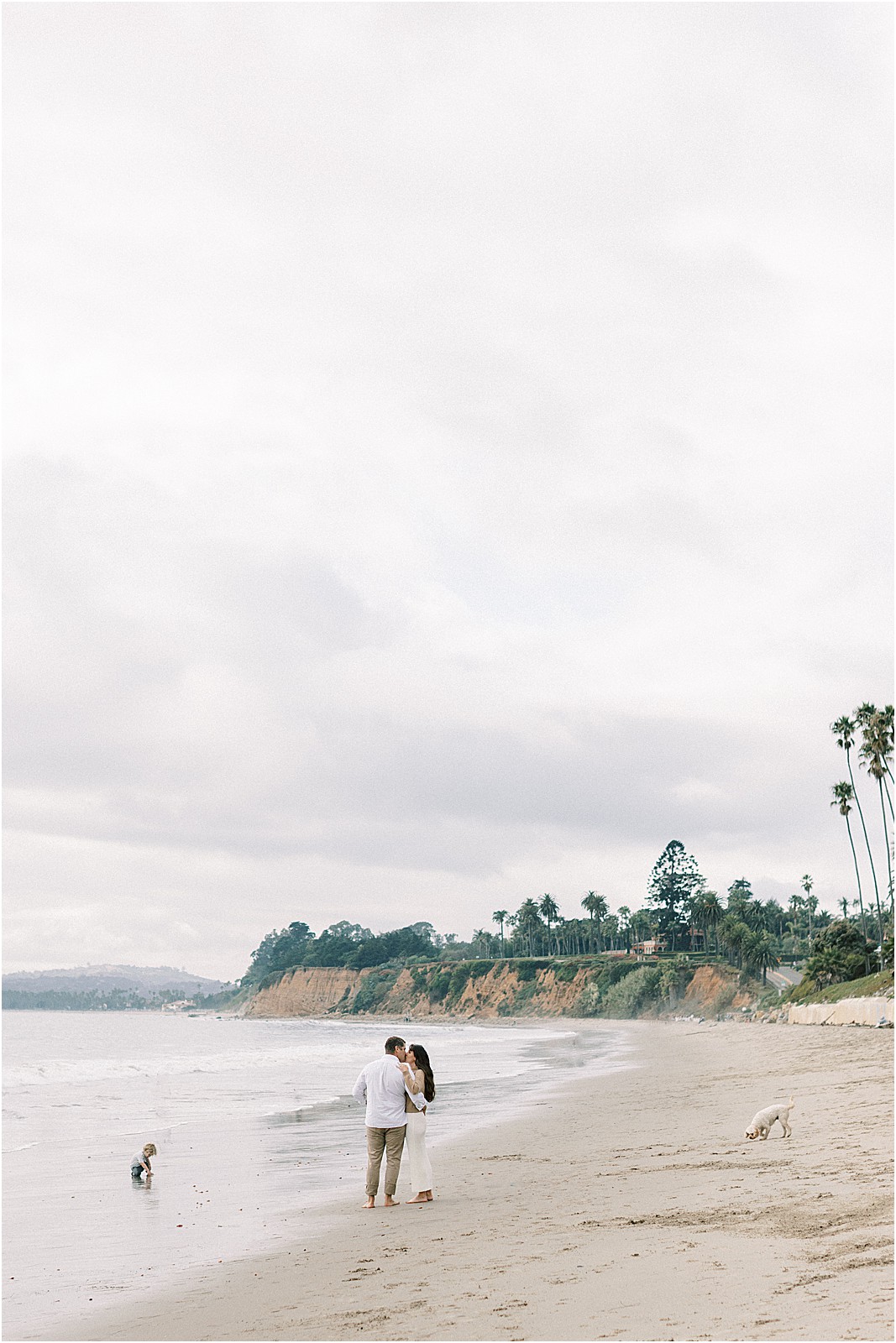 Parents' embrace with soft clouds, sea & palm trees in the distance 