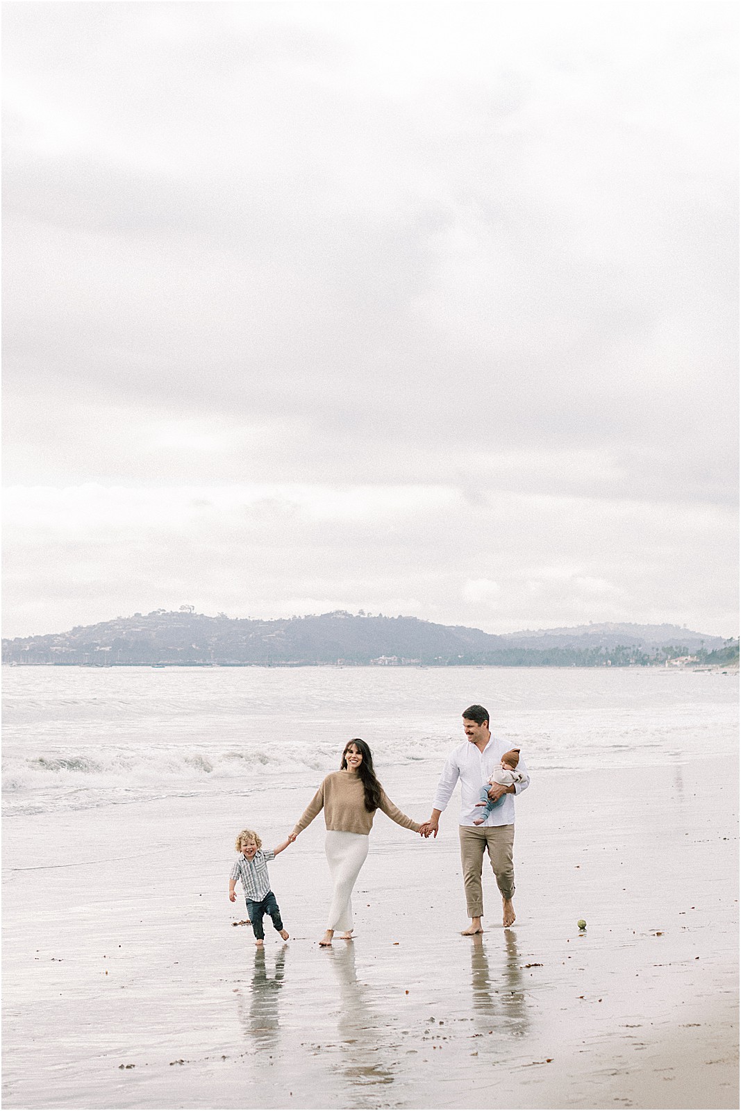 Family walking along Butterfly Beach under overcast skies during a photo session