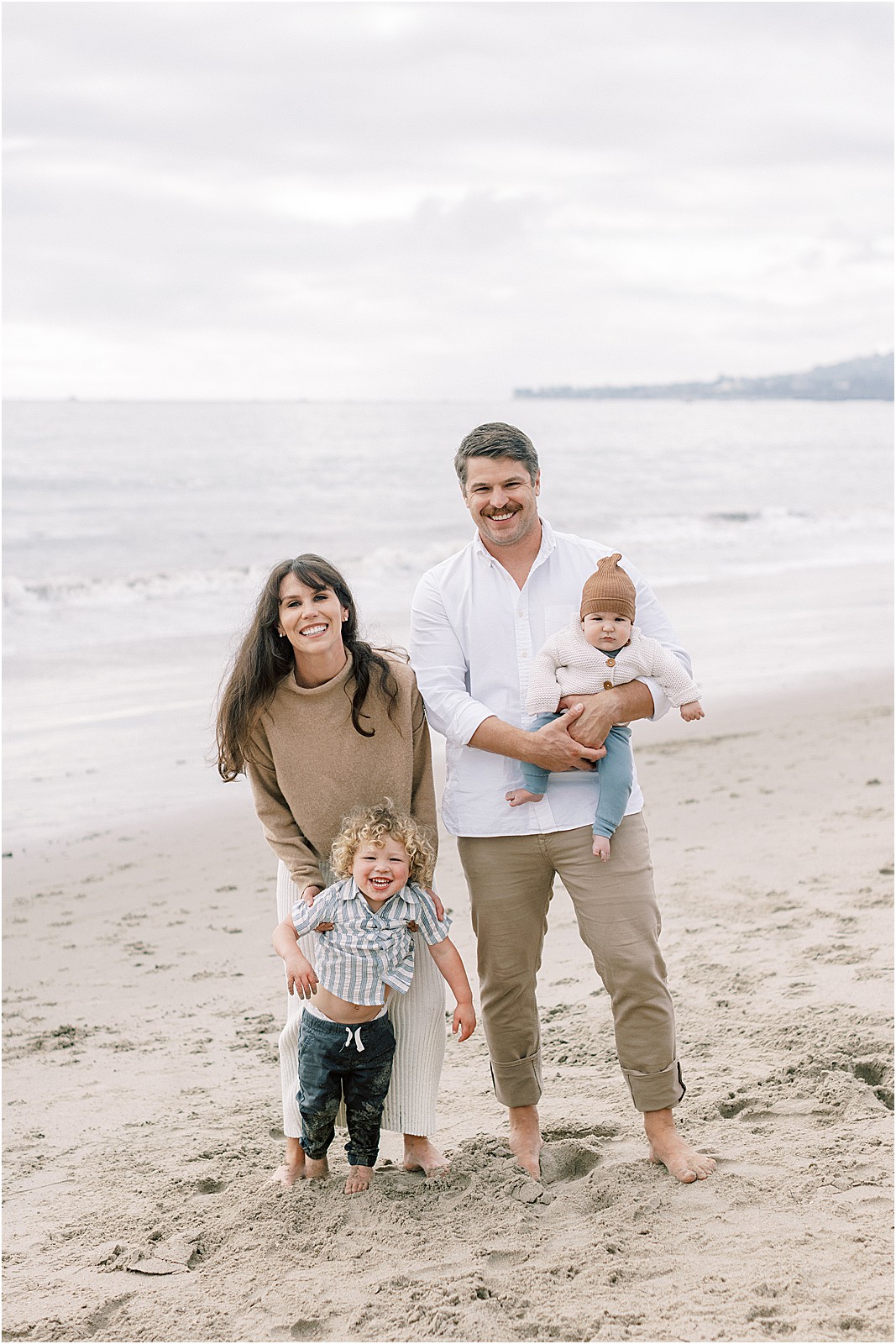 Vertical lifestyle family photo with muted tones and cloudy beach light