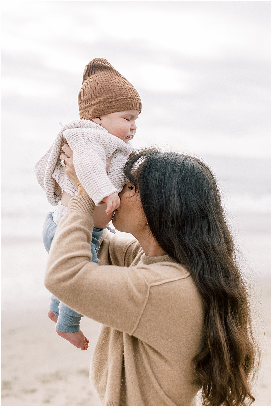 Vertical shot of mom kissing newborns belly at Butterfly Beach