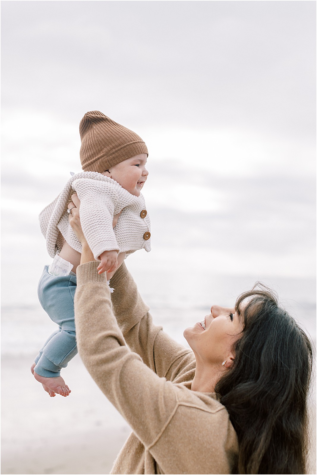 Vertical shot of mom lifting up her newborn at Butterfly Beach