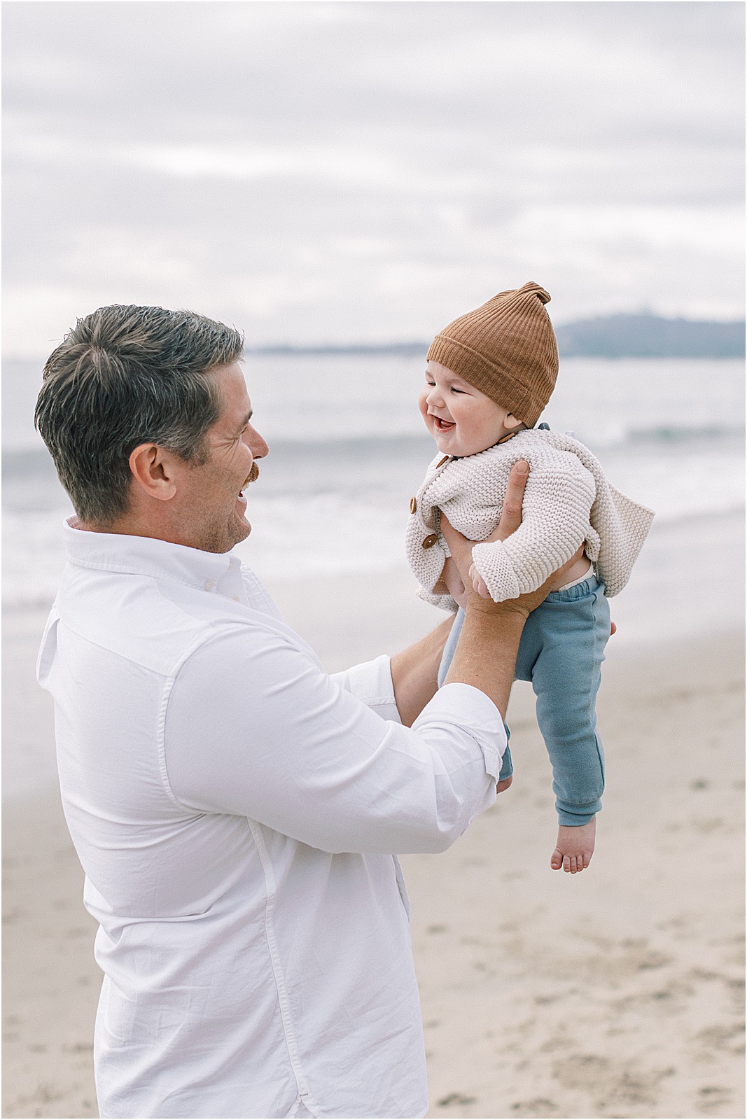 Dad holding up newborn during an overcast family session in Montecito