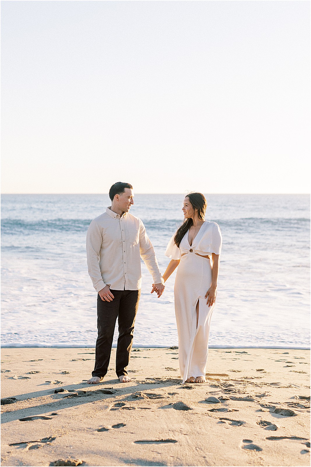 Couple smiling at each other with ocean breeze and soft light in Malibu.